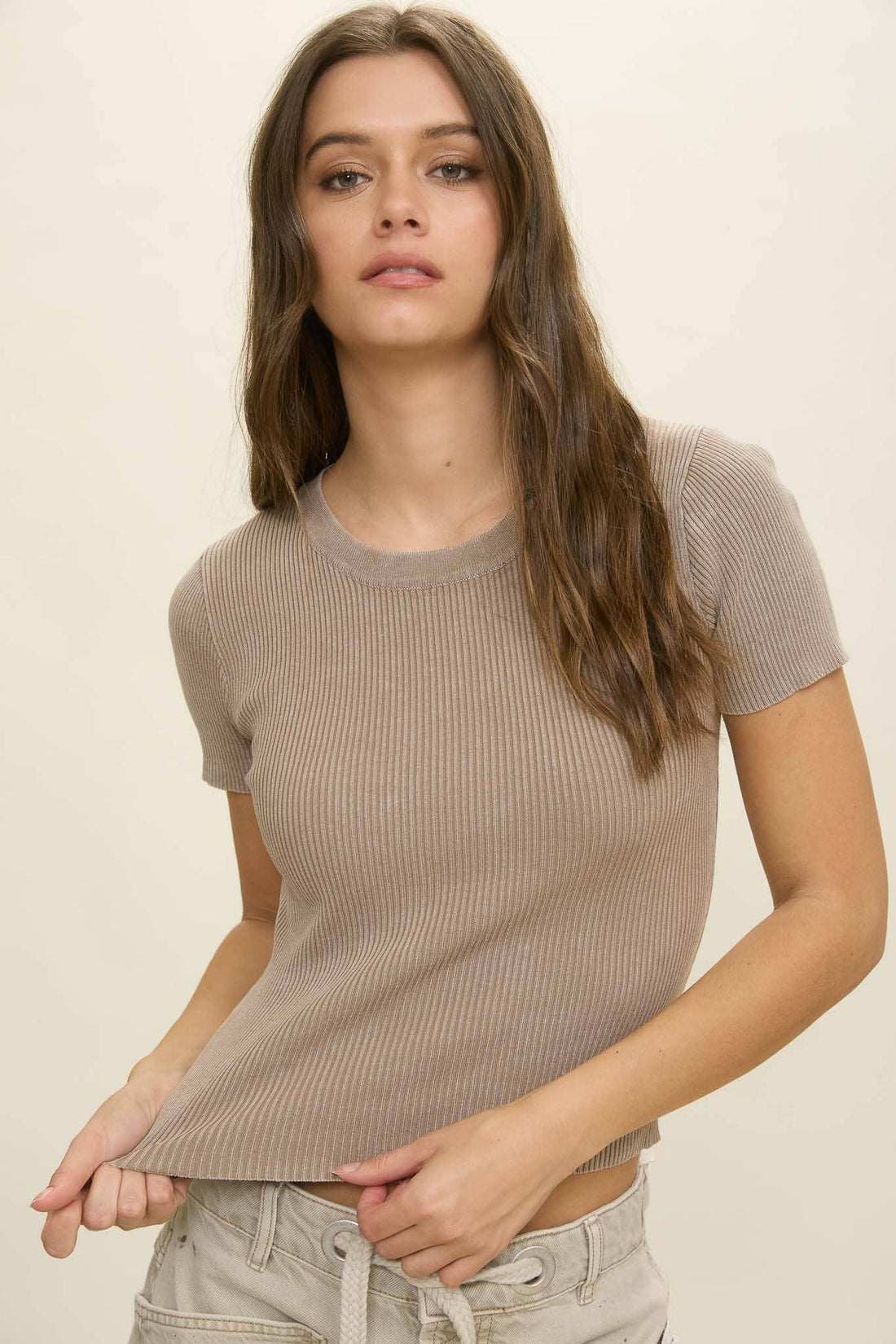 Woman wearing a ribbed brown t-shirt against a plain background