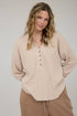Woman wearing a beige ribbed long-sleeve shirt and brown pants against a plain background