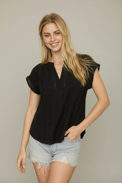 Black textured blouse with split neckline, short sleeves, and lace detail accents