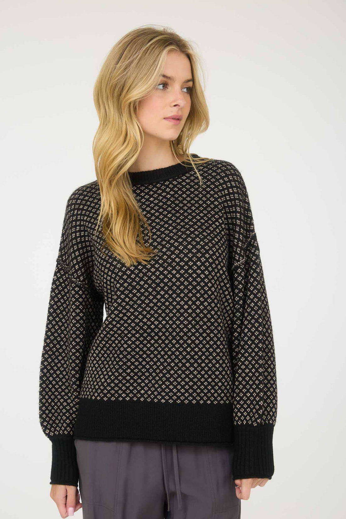 Woman wearing a black patterned sweater against a white background