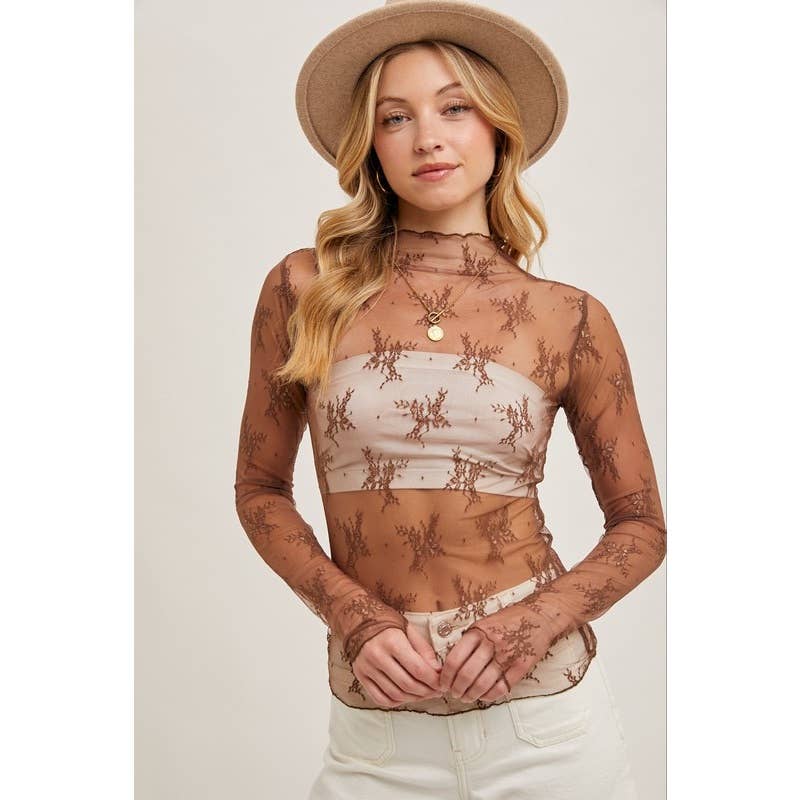 Woman wearing a sheer lace top with long sleeves and a beige hat on a plain background