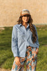 Women’s chambray blue western snap shirt with classic yoke stitching, silver snap buttons, and relaxed fit for everyday western style