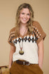 Woman wearing a patterned sweater with a necklace against a beige background