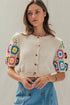 Neutral knit short sleeve cardigan with colorful crochet sleeves, button-front closure, and relaxed cropped fit with western-inspired styling