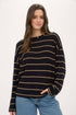 Woman wearing a black and gold striped sweater with blue jeans on a white background