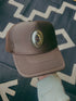 Brown trucker cap with a logo on a patterned fabric background