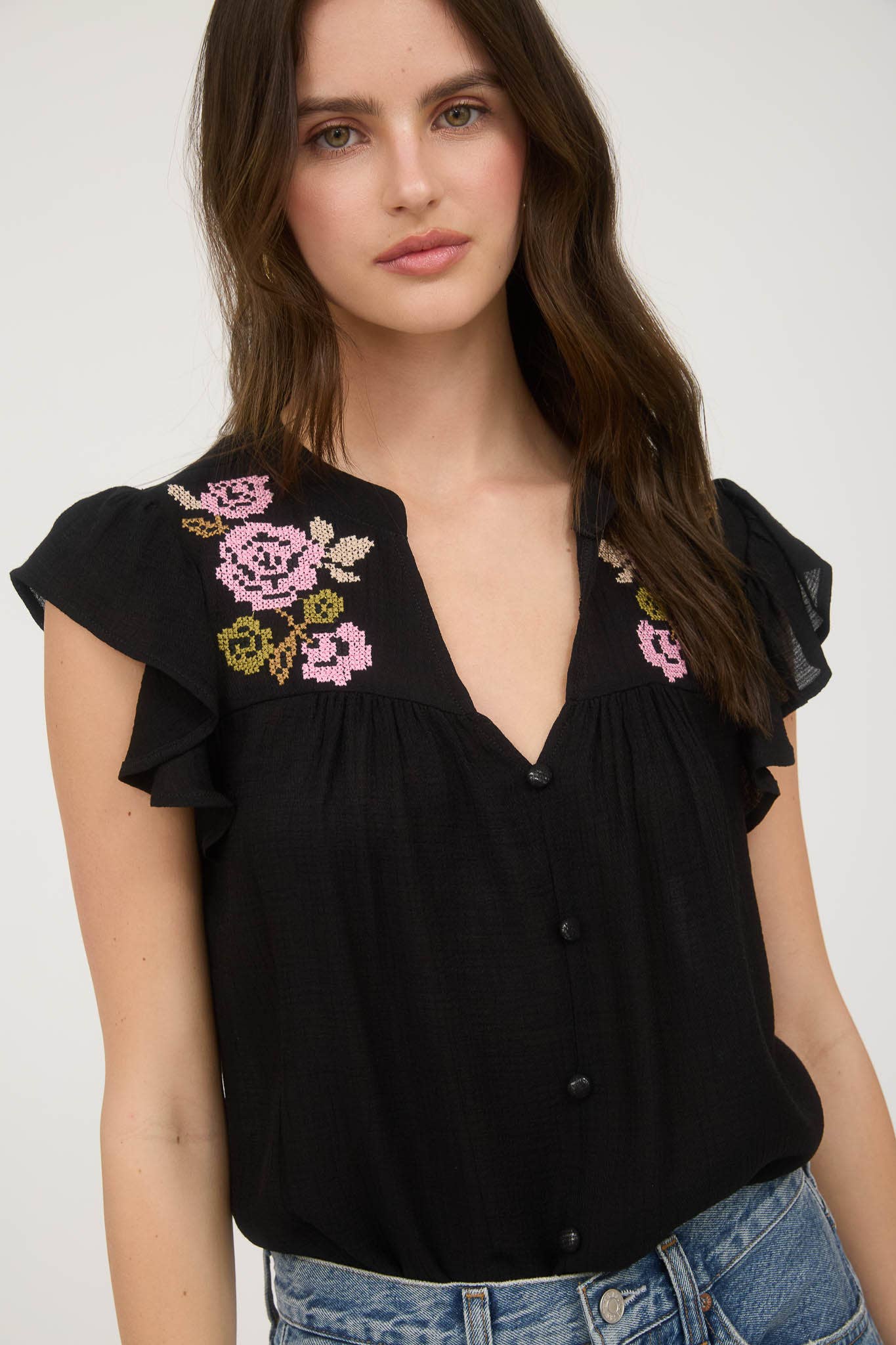Black blouse with floral embroidery, ruffle sleeves, and relaxed fit in a lightweight woven fabric
