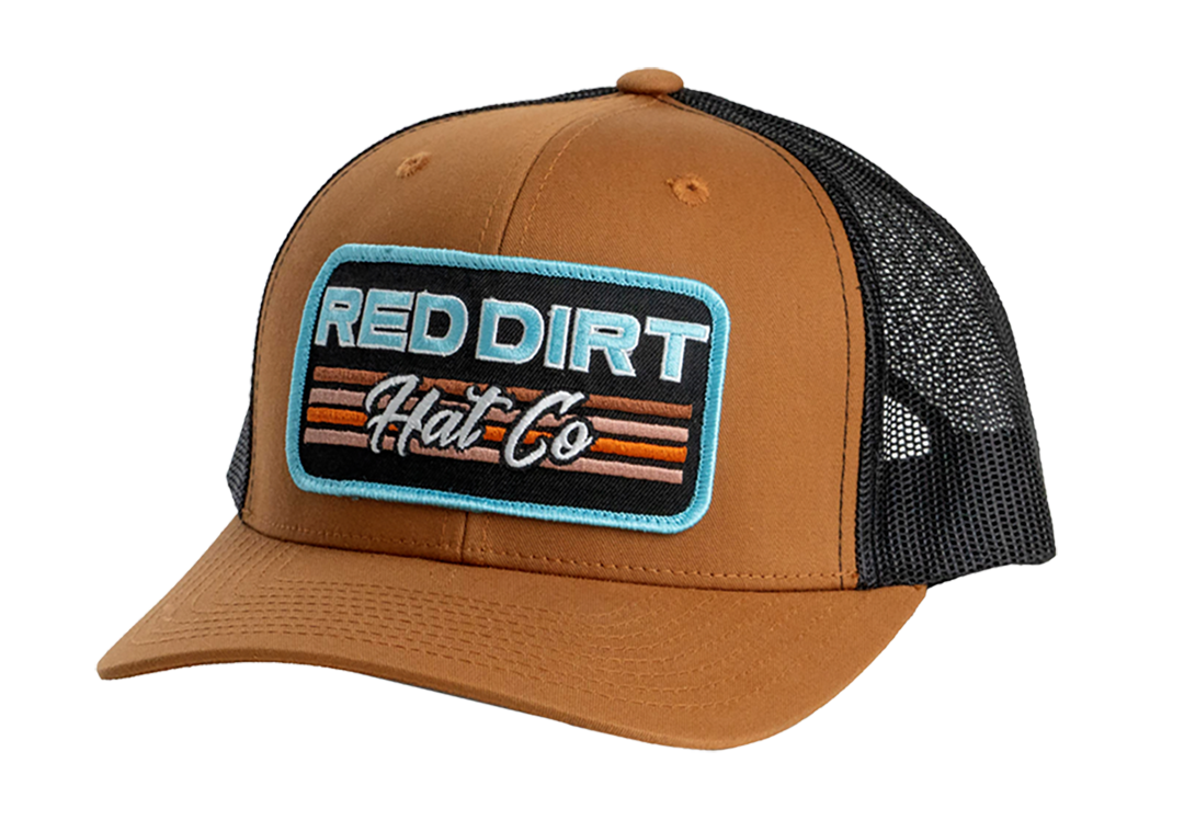 Red Dirt Hat Co. Between the Line Hat featuring a brown front panel, black mesh back, embroidered logo patch with retro stripes, and snapback closure.