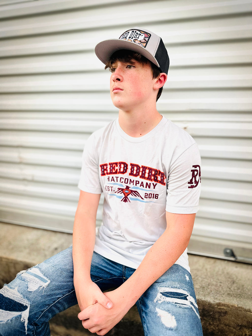 Unisex heather silver t-shirt (SKU: RDHC-T-151) featuring the exclusive "Aztec Thunderbird" design on the front and the Red Dirt Hat Co. branding on the left sleeve. Crafted from a soft cotton-poly blend.