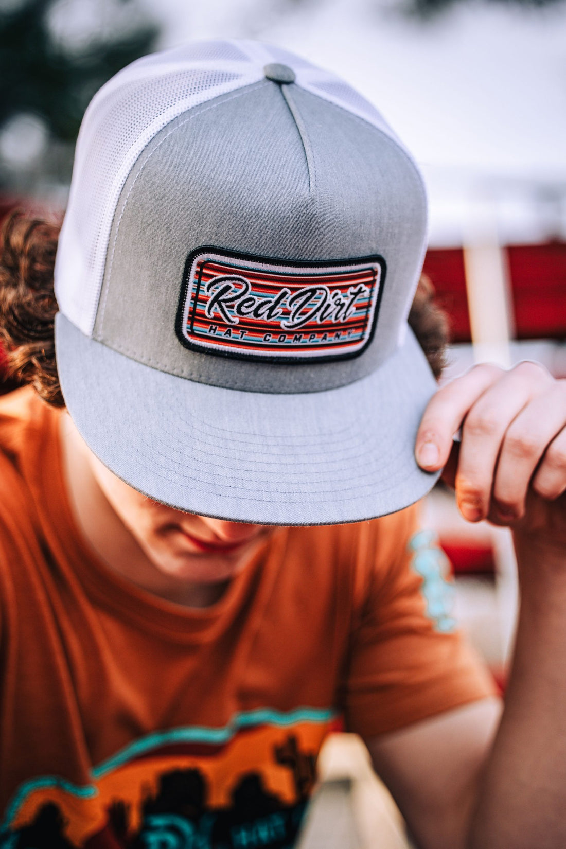 A heather gray and white trucker hat with an embroidered Serape 2023 patch featuring the &quot;Red Dirt Hat Company&quot; logo and a Southwestern serape-striped design.