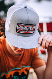 A heather gray and white trucker hat with an embroidered Serape 2023 patch featuring the "Red Dirt Hat Company" logo and a Southwestern serape-striped design.