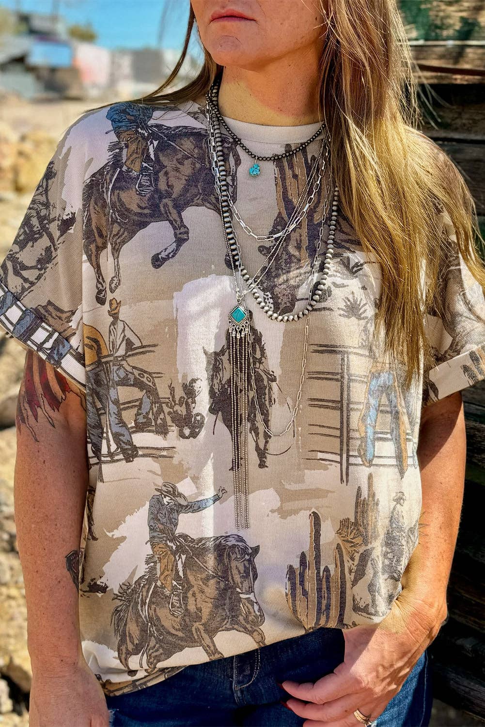 Roughstock Rodeo Tee – Western cowboy graphic t-shirt featuring a vintage rodeo print with bronc riders and desert scenery. Relaxed fit with soft polyester-spandex fabric, perfect for western style enthusiasts.