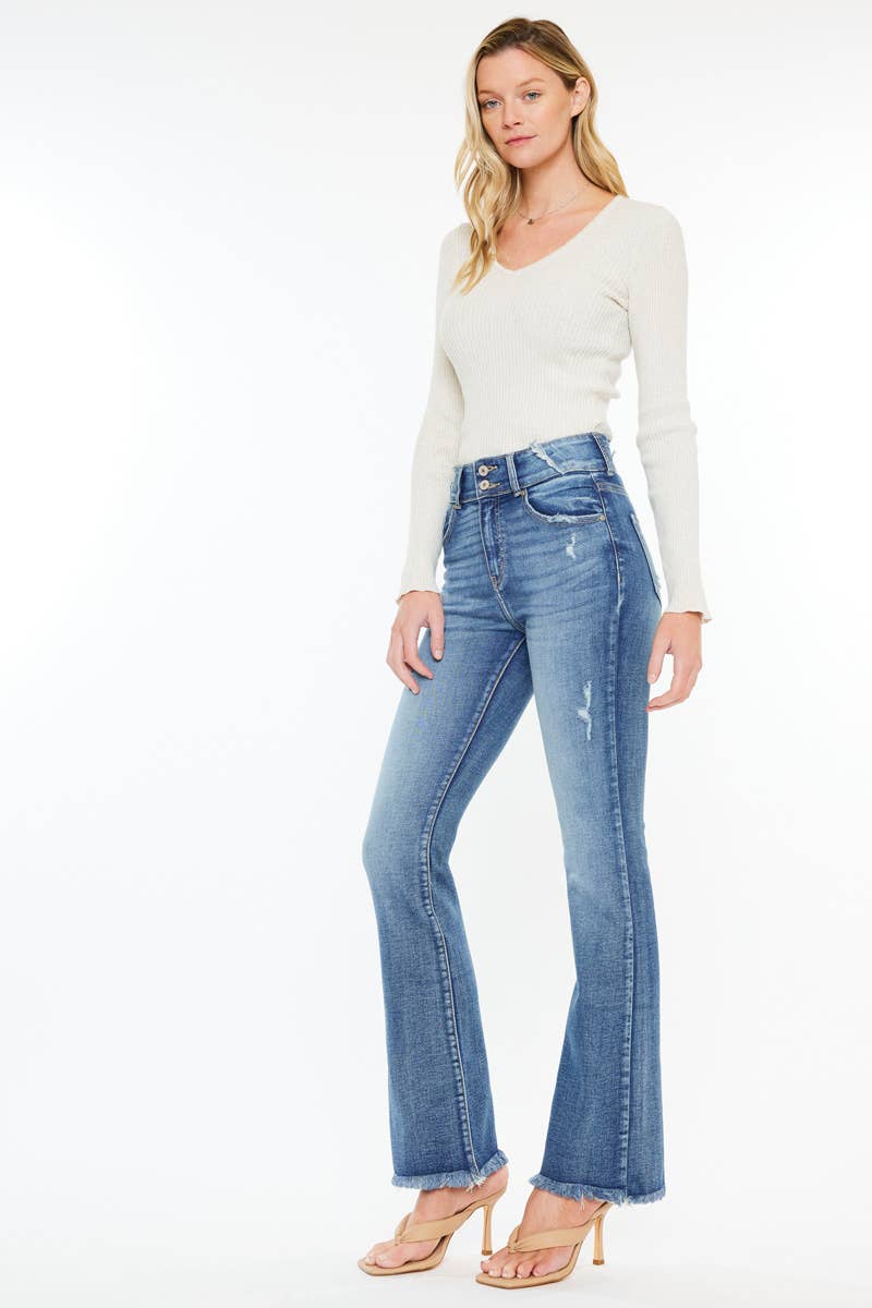 Rustler’s Road Denim – High-rise bootcut jeans in a medium wash with stretch, featuring pleat and dart details, a raw edge waistband, and frayed hem. Designed for a flattering western-inspired fit.